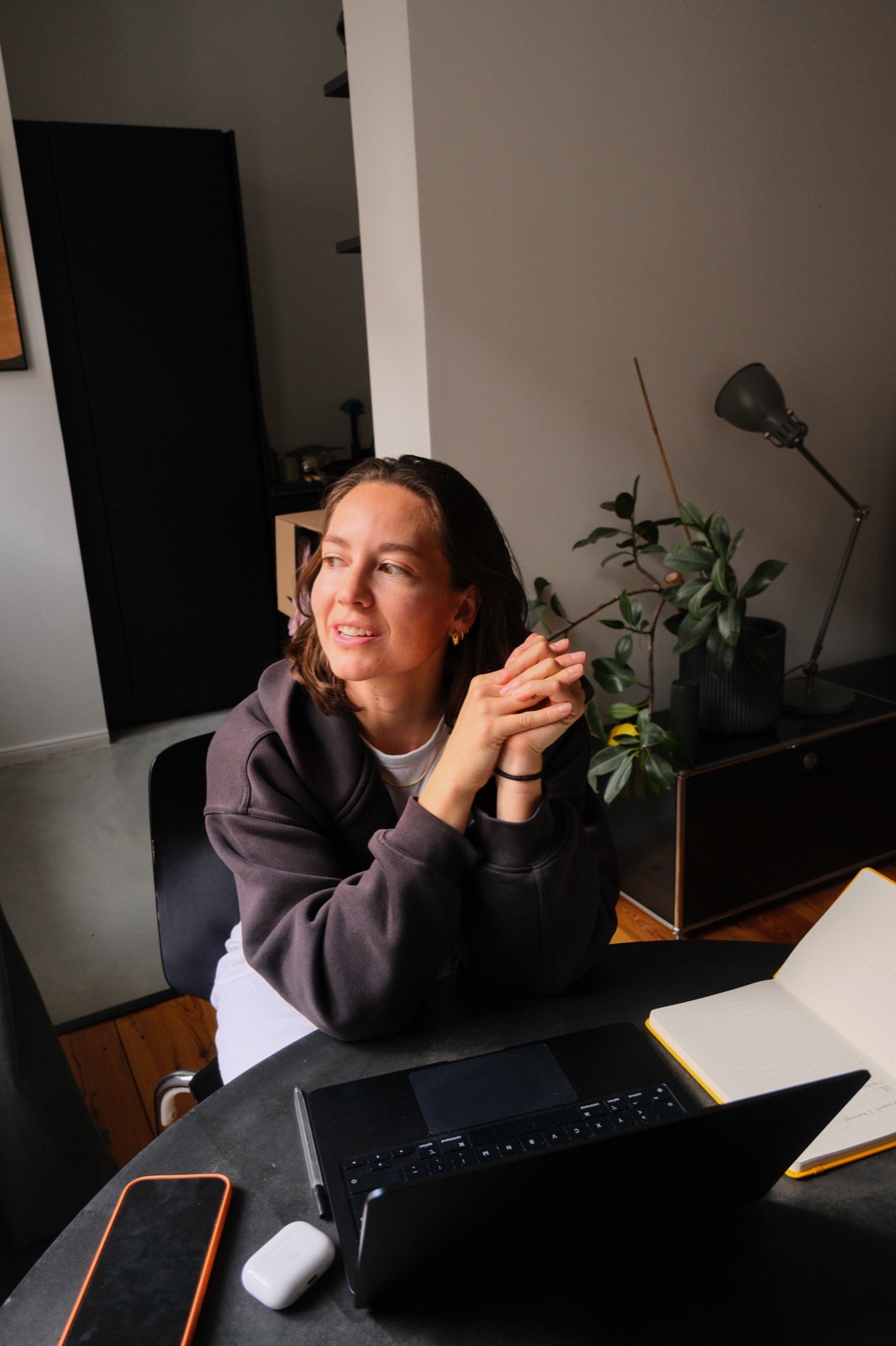 Fiona Raikes at her desk, hands clasped, mid-conversation with a notebook and laptop in front of her